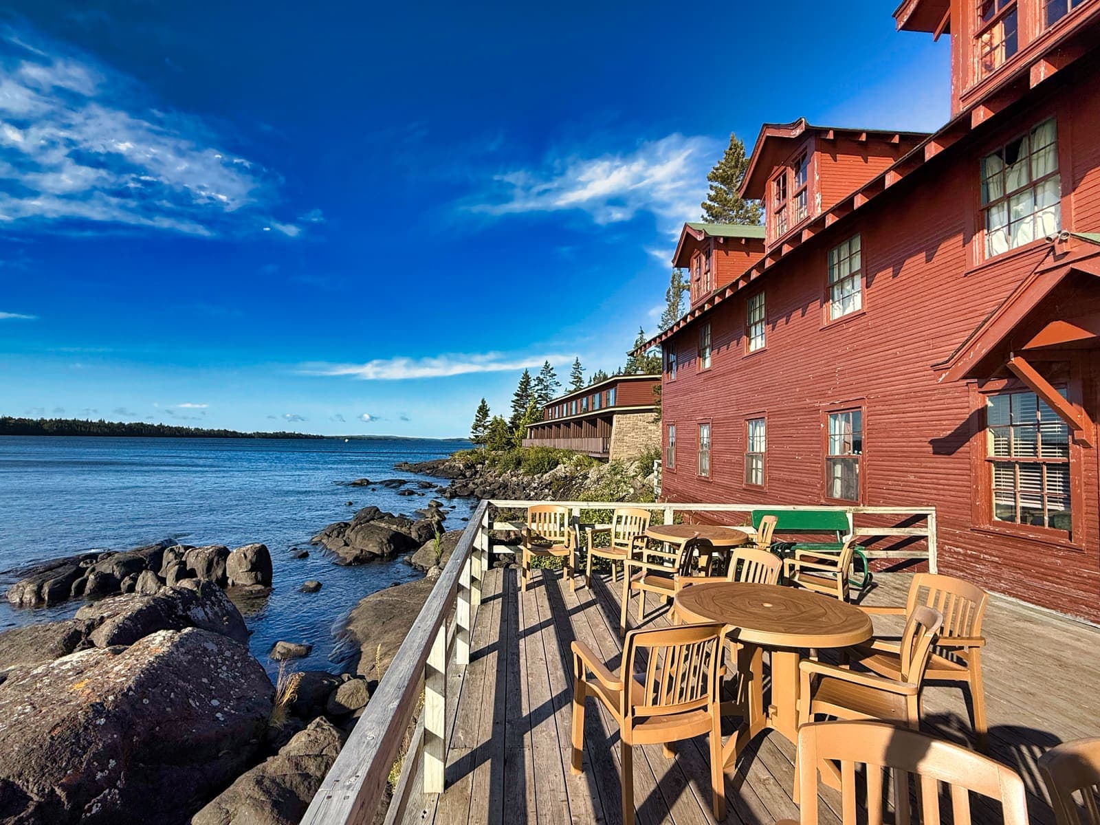 The deck of the Rock Harbor lodge beside the rocky shore and calm lake